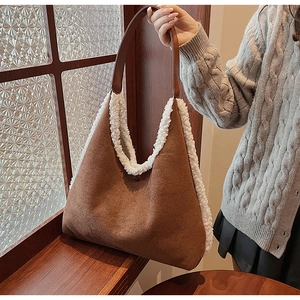 Detailed view of brown suede tote bag featuring white faux fur trim and leather shoulder strap