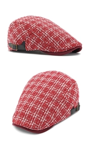 Detail van rode tweed baret met lederen verstelriempje en metalen gesp aan de kant