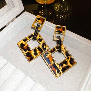 Detailed close-up of leopard print geometric earrings in a velvet jewelry box
