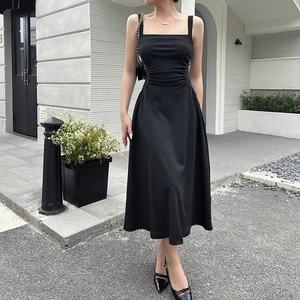 Detailed view of the pleated waist and flowing fabric on this black A-line midi dress