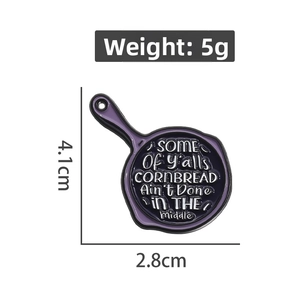 Detailed view of enamel frying pan brooch with geometric lettering and dimensions