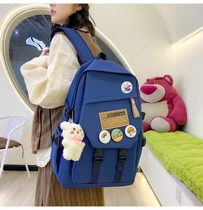 Detail of navy blue nylon backpack featuring side straps and cute white bear keychain