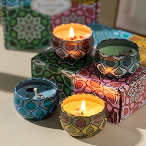 Set of four colorful scented candles in metal tins with geometric patterns and gift box