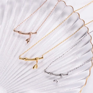 Detailed view of bamboo style necklaces in gold, rose gold and silver on a glass tray