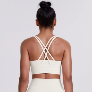 Detail view of cream sports bra with cross-back thin straps and high-waist yoga leggings