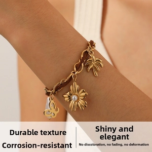 Dettaglio del bracciale a catena placcato oro con fiore di perla, farfalla e ciondoli