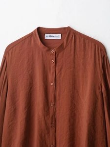 Close-up of rust brown shirt with stand collar and textured pleated fabric detail