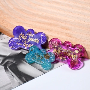 Détail de pendentifs en résine en forme d'os avec paillettes, feuilles d'or et texte