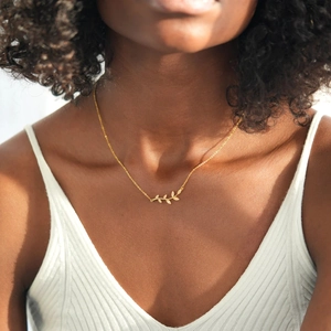 Elegant gold leaf branch necklace with shimmering stones on a female model