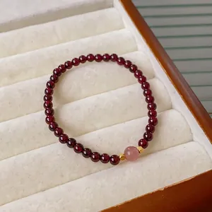 Garnet beaded bracelet with strawberry quartz and gold cubes in a velvet display case