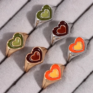 Detail of colorful enamel heart rings in gold and silver finish on gray velvet display