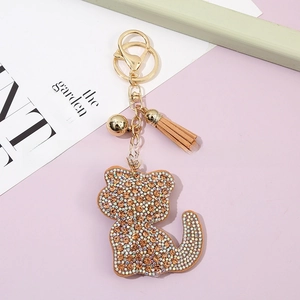 Detailed view of crystal cat keychain featuring gold bell, tassel, and lobster clasp