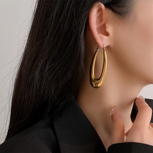Close-up of a model wearing a polished gold teardrop U-shaped hoop earring