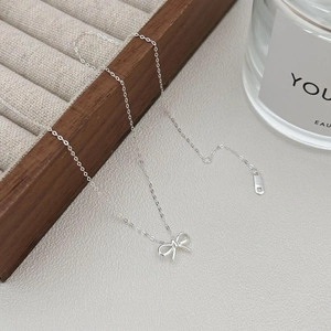 Elegant 925 sterling silver bow necklace with thin chain on a minimalist display