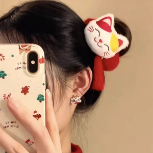 Detail showing plush Maneki Neko hair tie with red tassels on hair bun hairstyle