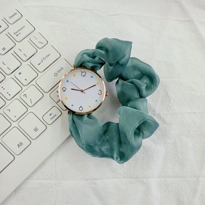 Elegant green ribbon strap watch with white dial and rose gold case on a soft background
