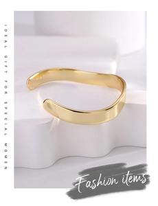 Detailed view of irregular wide gold brass cuff bracelet on a minimalist display stand