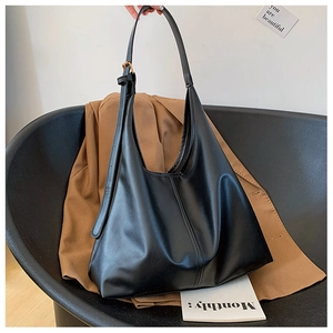 Detail shot of a black leather tote bag on a chair with casual fashion accessories