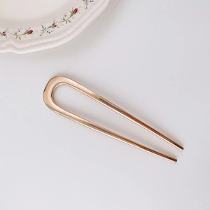 Elegant gold U-shaped metal hairpin on minimalist white background for daily styling