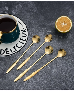 Golden flower and heart shaped stainless steel dessert spoons on a dark green saucer