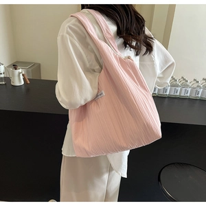 Detailaufnahme einer rosa gefalteten Stofftasche mit gewebtem HAND MADE Etikett am Gurt