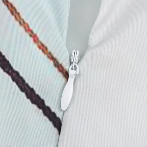 Detailopname van een witte onzichtbare rits op de maxi-jurk van satijn met print