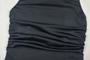 Close-up of ruched detail and fine texture on black high neck backless bodycon dress