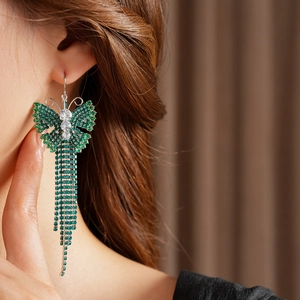 Dettaglio di gancio per orecchio vintage con farfalla in zircone verde e lunghe nappe