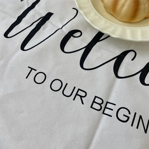Close-up of white linen placemat with minimalist black text and ceramic wave plate