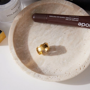 Detailed view of wave textured 18k gold plated stainless steel ring on marble tray