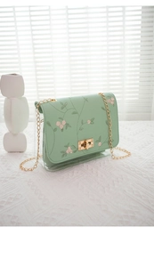 Close-up of pink flower embroidery and golden twist lock on light green PU leather bag