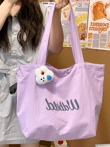 Detail of purple large-capacity tote bag with drawstring closure and white plush charm