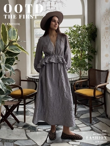 Détail d'une robe grise plissée avec col en V en dentelle et manches lanternes volantées