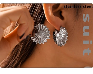 Macro shot of silver pleated flower stud earrings in stainless steel on ear