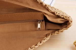 Macro view of brown fabric lining and metal zipper closure inside straw woven bag
