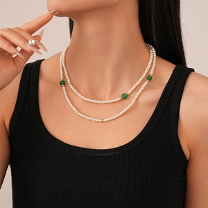 Gros plan d'un collier de perles double couche avec agates vertes sur un haut noir