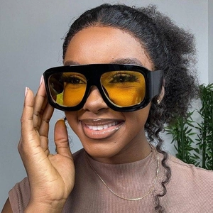 Fashionable square black sunglasses with yellow lenses worn by a smiling model indoors