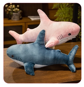 Pink and blue shark plush toys made of soft material on a wooden table setup