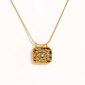 Macro detail of square gold pendant with evil eye turquoise and zircon accents