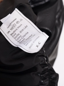 Macro view of laundry care label showing 100% polyester material and washing instructions