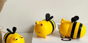 Trois porte-cure-dents mignons en forme d'abeille jaune et noire sur surface décorative