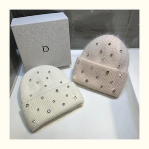 Detailed view of plush rabbit fur beanie hats in white and pink with sparkling rhinestones
