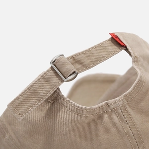 Close-up of adjustable metal buckle and strap on khaki distressed baseball cap