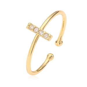 Macro detail of gold open ring featuring a rectangular bar set with five clear cubic zirconia