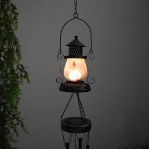Detail of iron hollow moon solar lantern with warm light and metal wind chime tubes