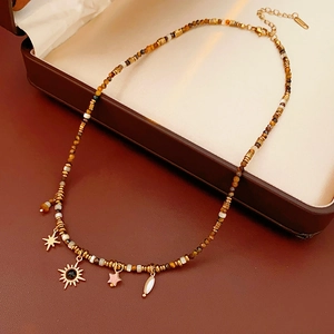 Detailed shot of ethnic beaded necklace with sun, star, and stone charms in a jewelry box
