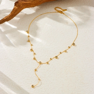 Macro shot of gold Y-shaped fringe necklace with sparkling diamond circular pendants