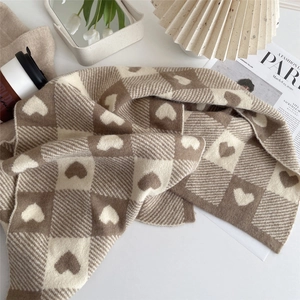 Close-up of knitted heart pattern scarf with brown and white checkerboard texture