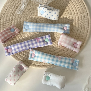 Detailed fabric cable organizers in plaid and polka dot patterns with heart snap buttons