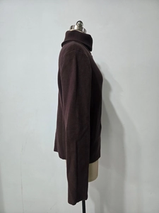 Detail view of the brown ribbed knit texture and side profile on a long-sleeve sweater